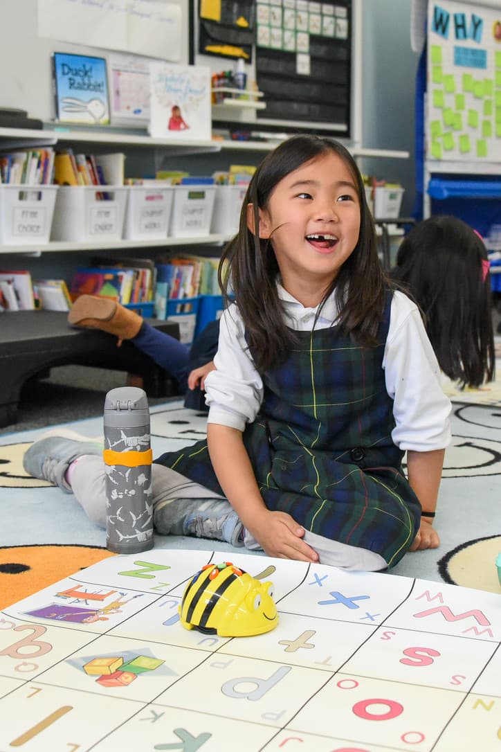 A first grader smiling during a classroom technology activity