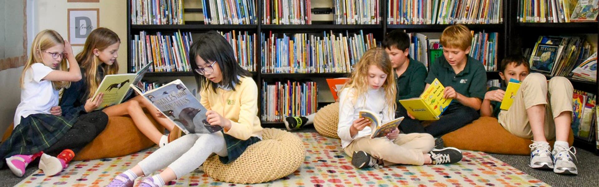 Students reading together on cushions in front of library bookshelves