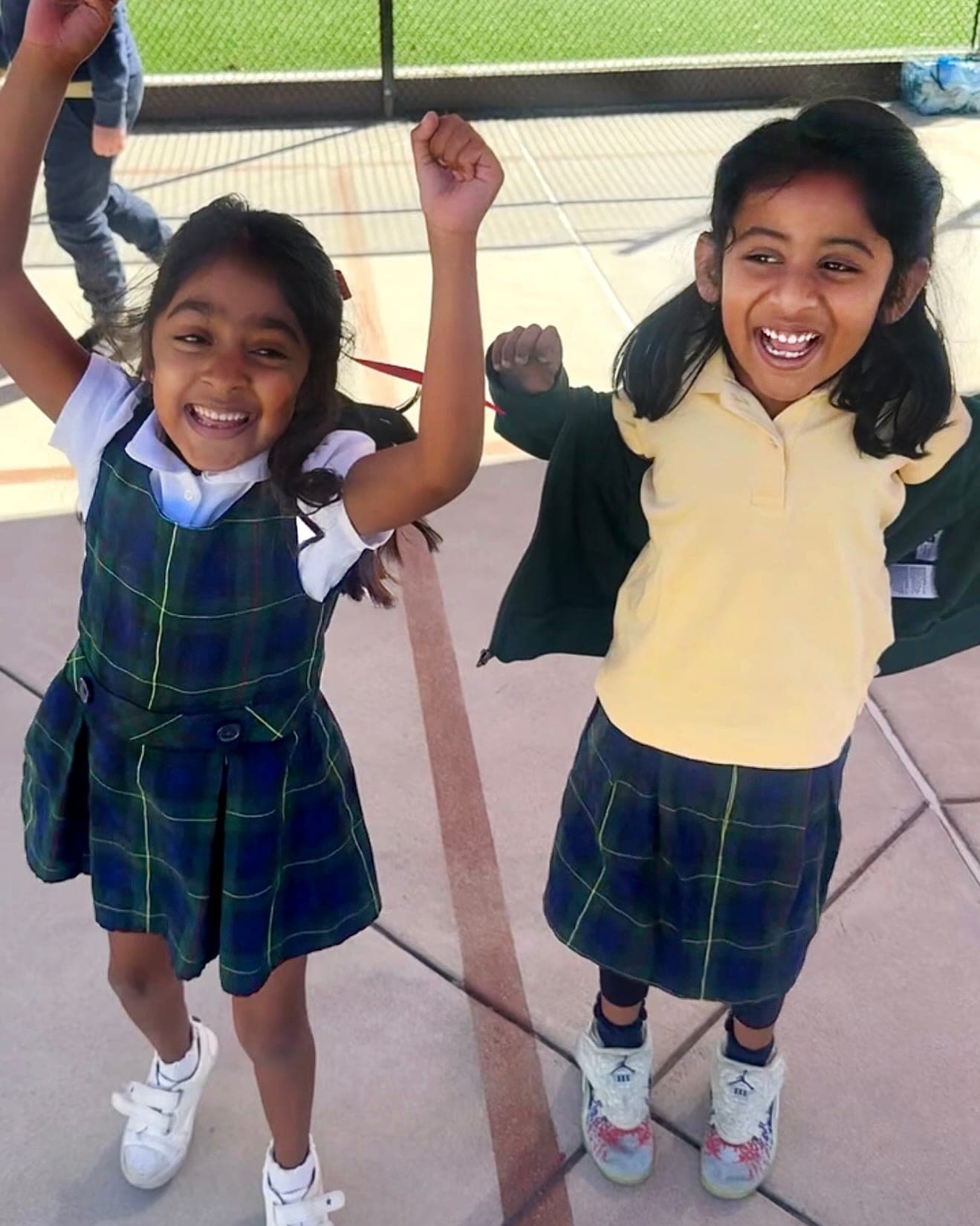 Two students cheering with raised arms on the playground during aftercare