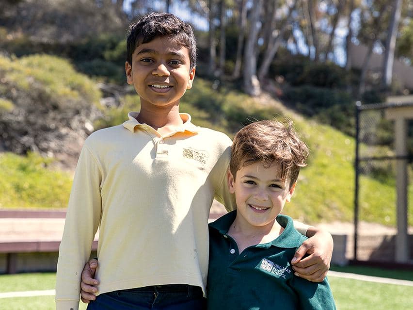 Two students, arms around each other, on the field