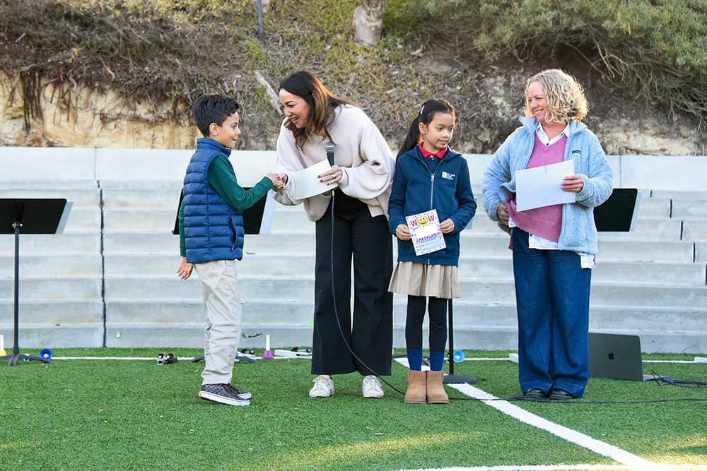 Students receiving recognition awards outdoors at an assembly