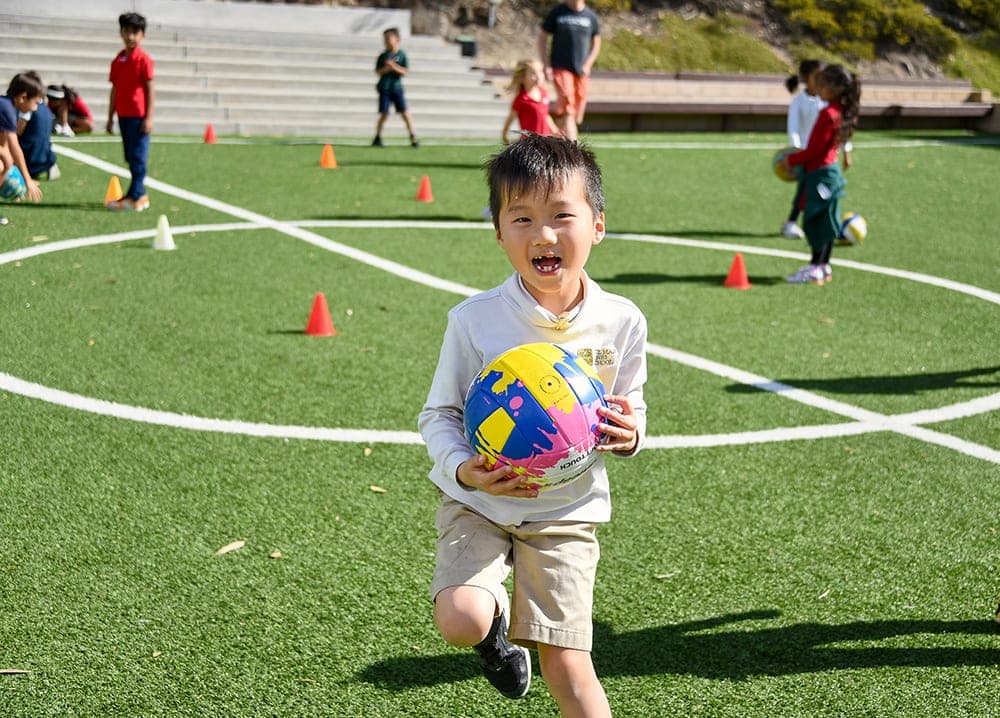 A student running with a ball during PE on the field