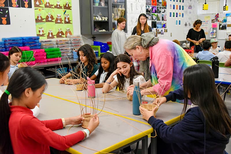 Students weaving baskets together with their teacher in the art studio