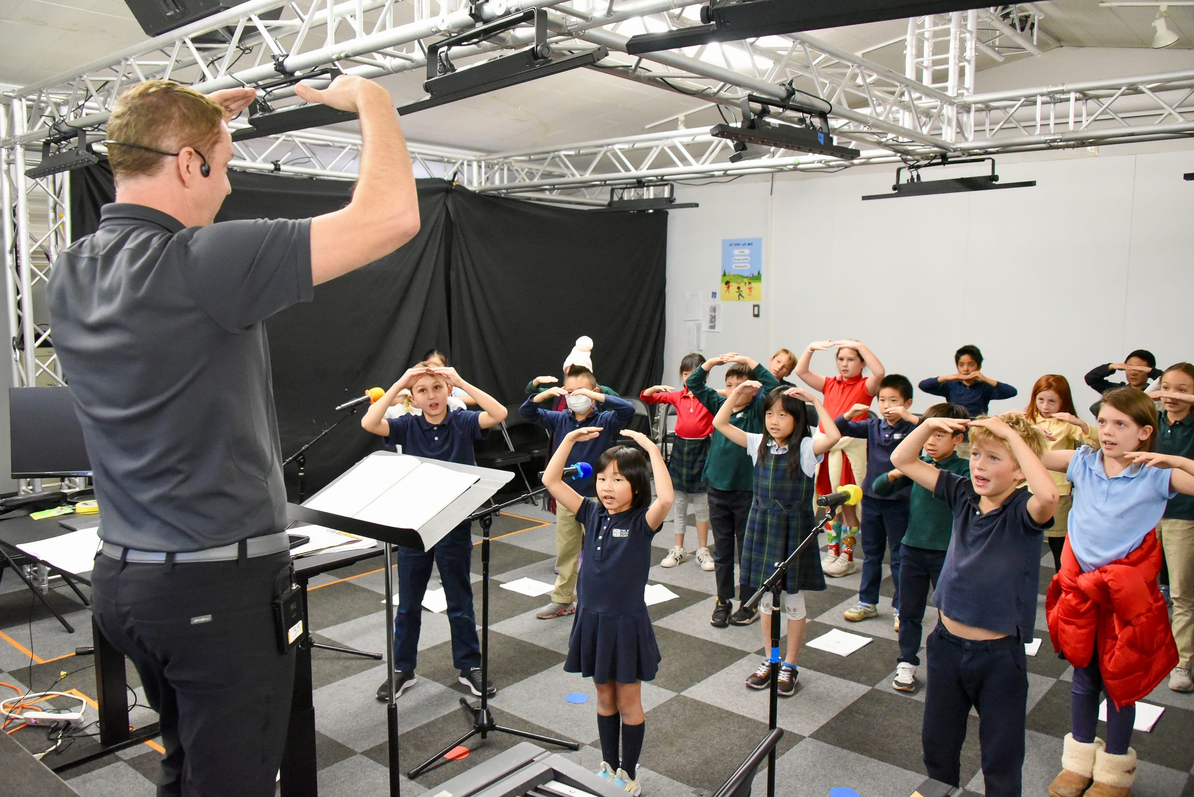 Students rehearsing with a music teacher in the black box theater