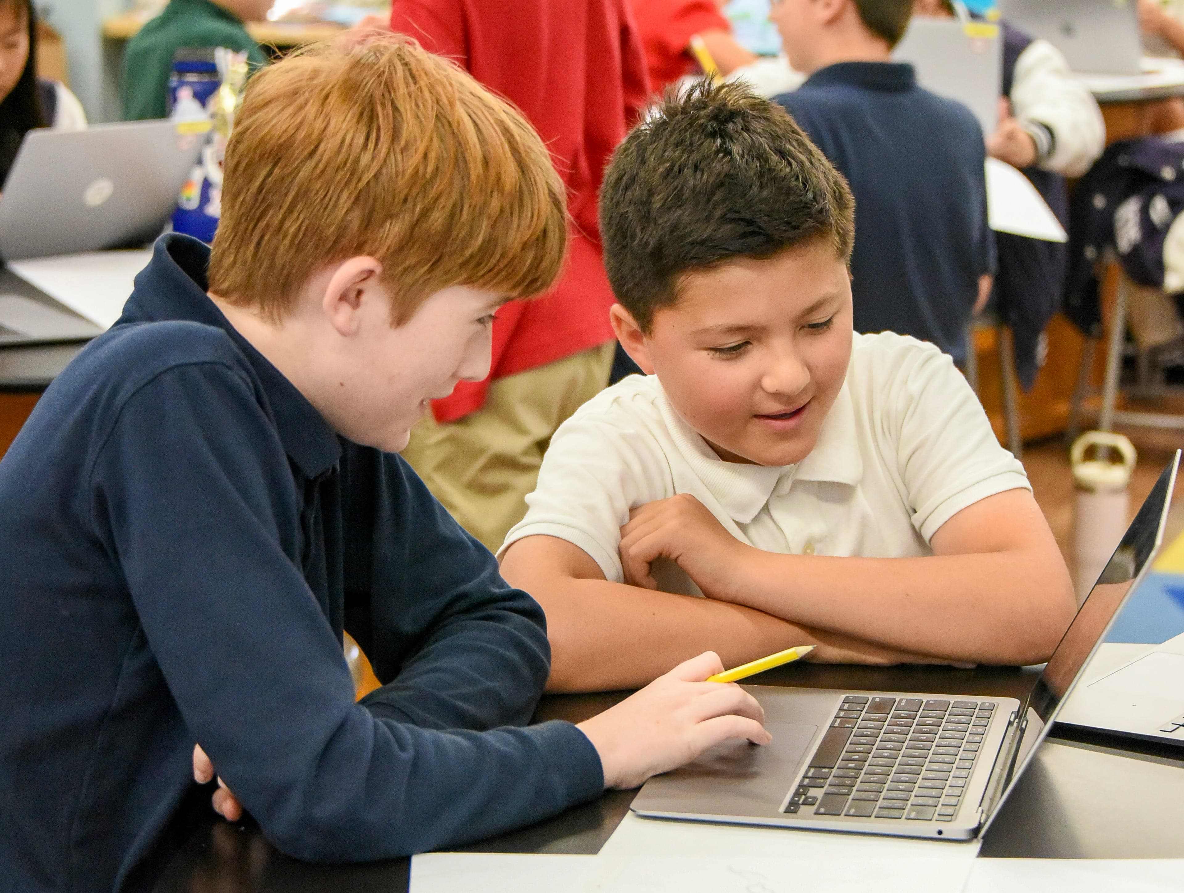 Two students working together on a laptop in class