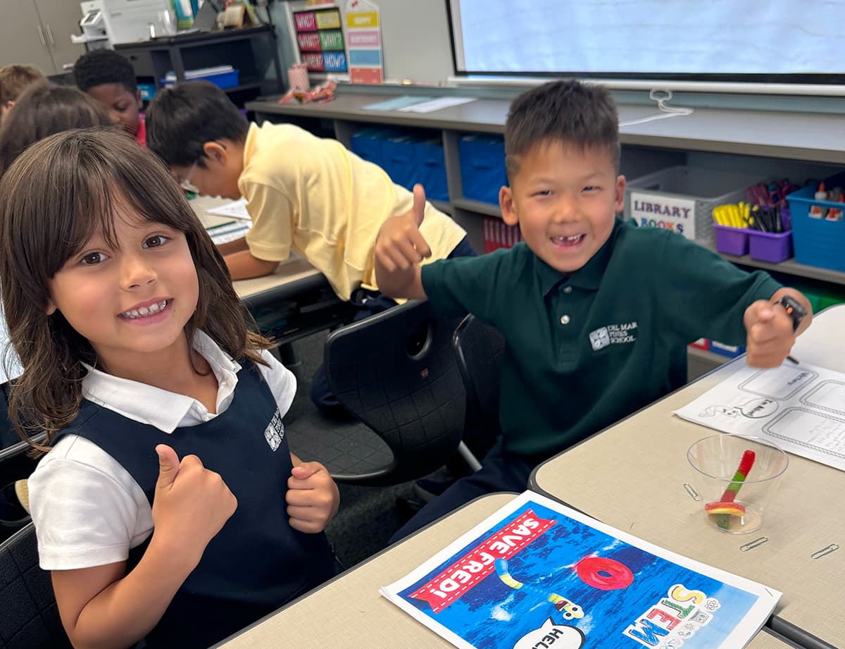 A teacher and two students in headphones smiling at a table with an iPad and worksheets