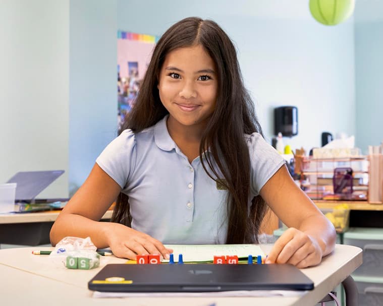 A student smiling at her desk during a math lesson