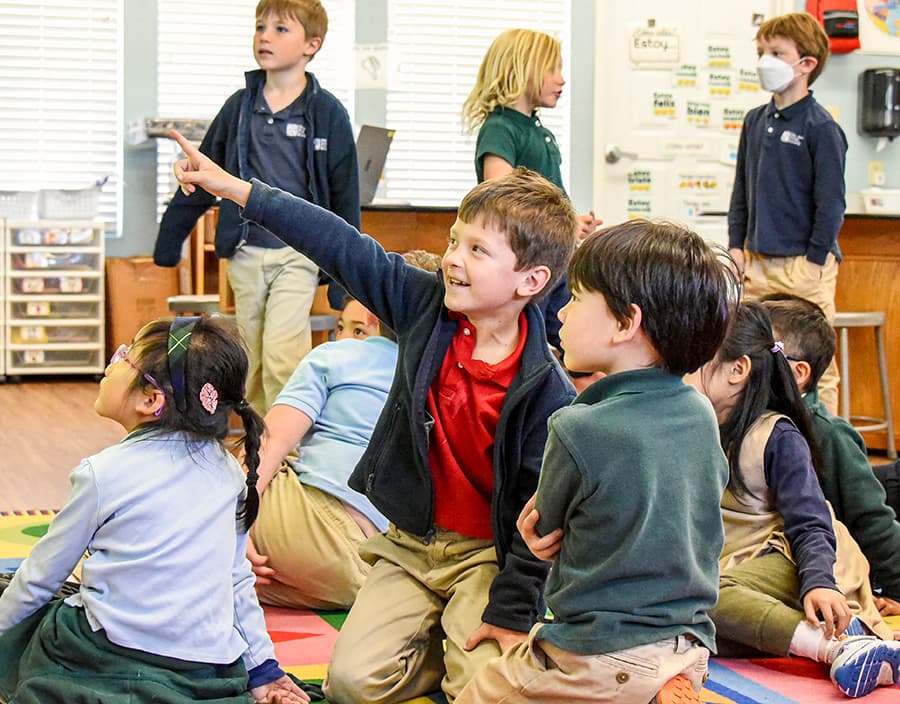 Students pointing and engaged during a classroom lesson
