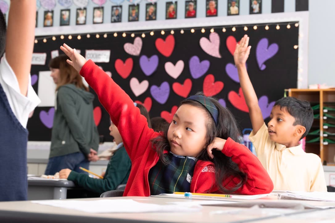 First graders raising their hands in class