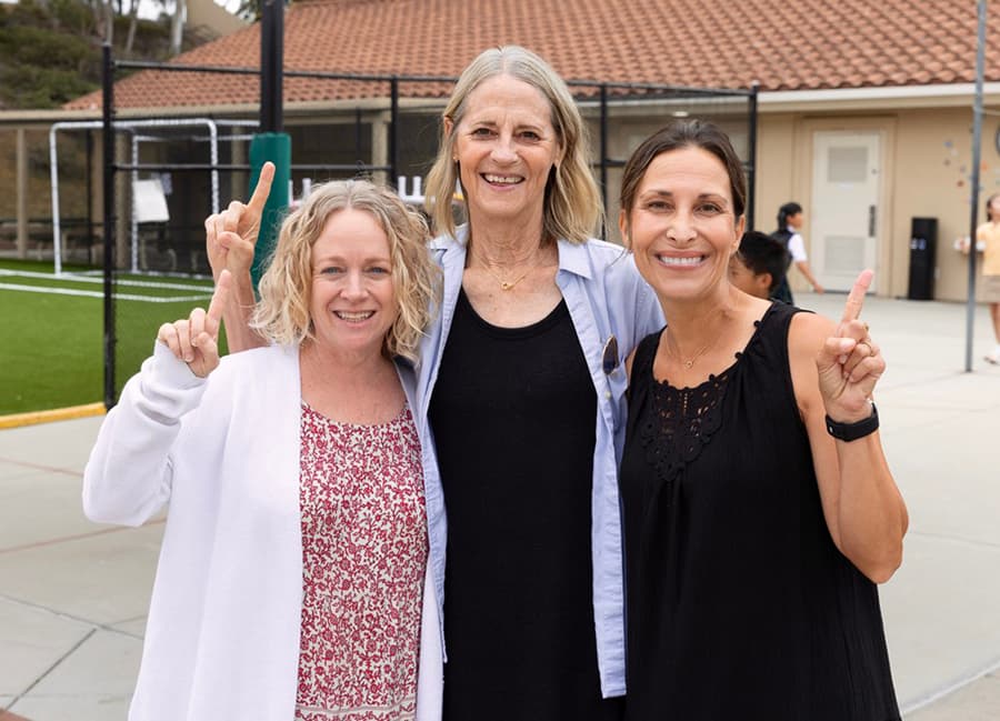 Three teachers smiling together on the playground