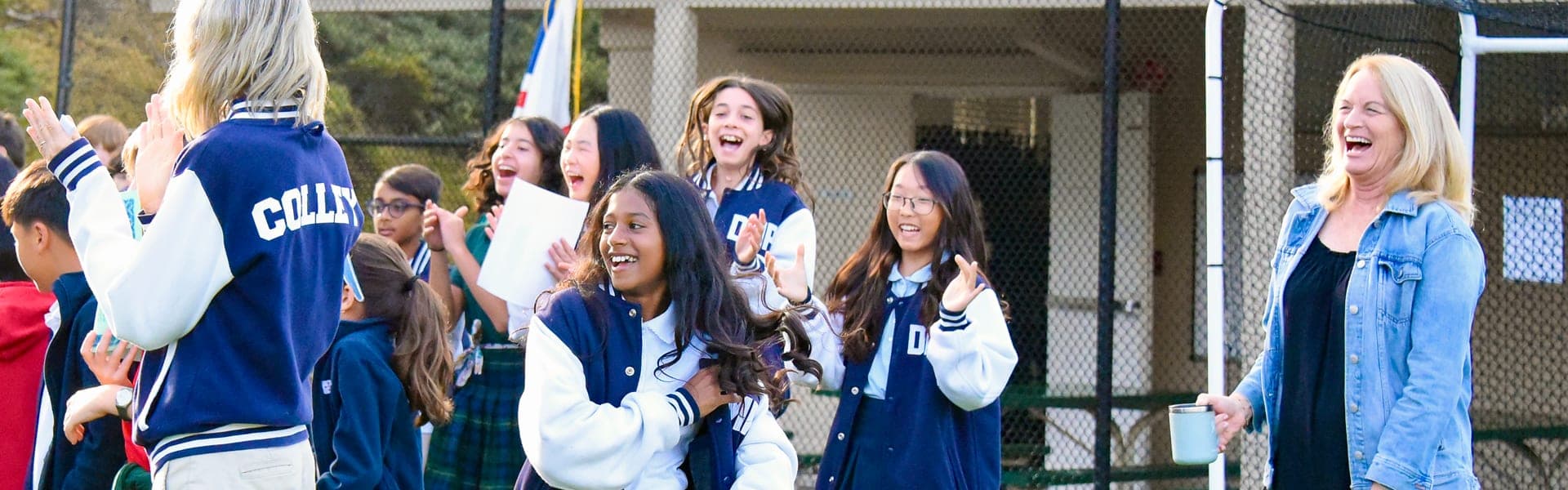 Students and a teacher cheering together on the field