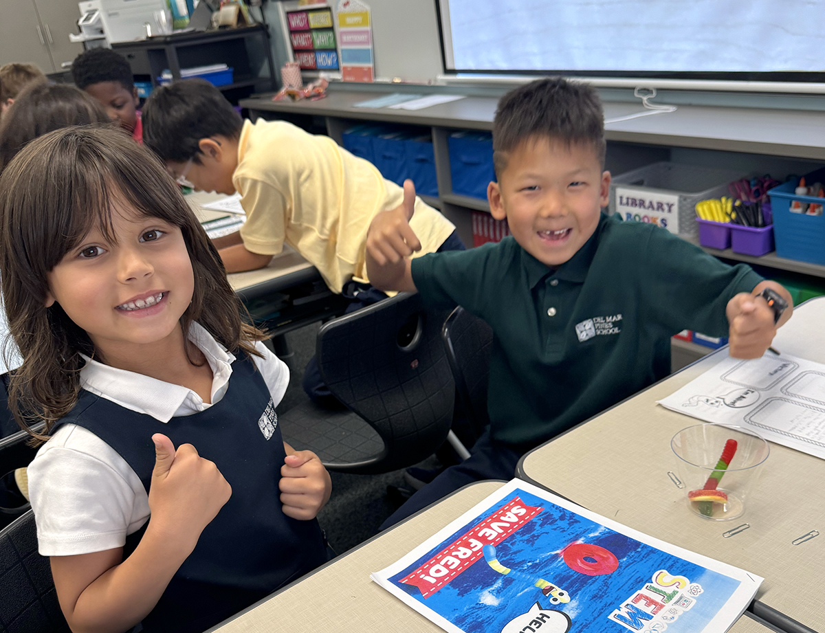 A teacher and two students in headphones smiling at a table with an iPad and worksheets